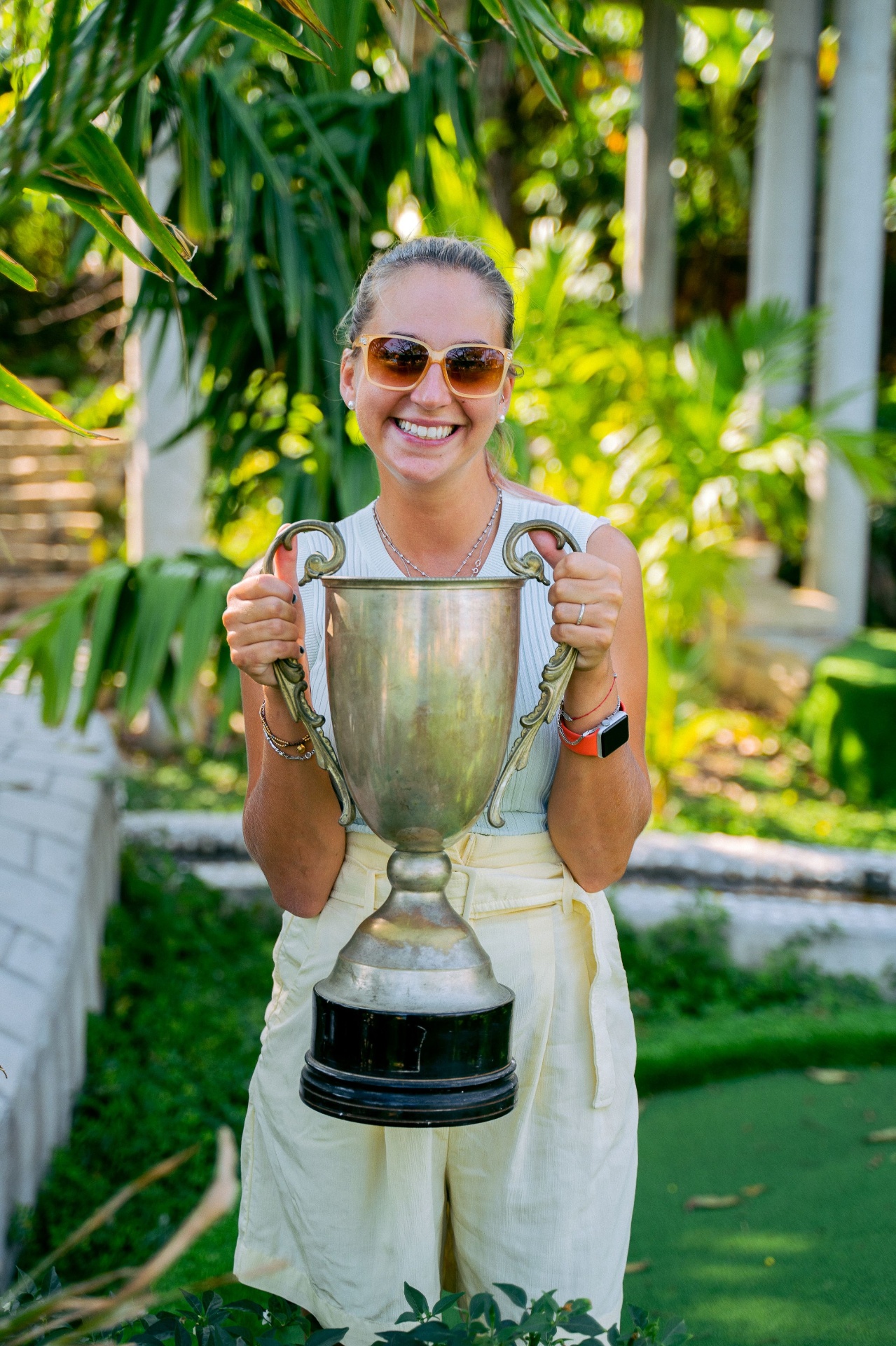 Smiling golfer holding a large trophy at a corporate golf tournament